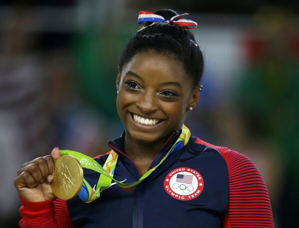 FILE - United States gymnast Simone Biles displays her gold medal for floor during the artistic gymnastics women's apparatus final at the 2016 Summer Olympics in Rio de Janeiro, Brazil, Aug. 16, 2016. The 27-year-old Biles is returning for a third Olympics, where she will try to earn an all-around gold to bookend the one she captured in 2016 in Rio. (AP Photo/Rebecca Blackwell, File)