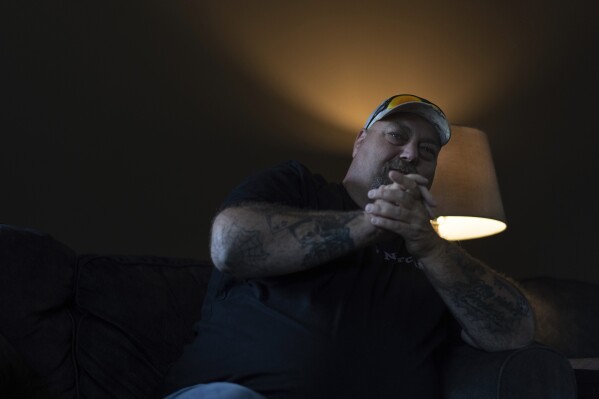 Cory Kinn, men's home coordinator and criminal justice liaison at FOCUS Recovery and Wellness Community, sits in the men's recovery house living room in Findlay, Ohio, Friday, Oct. 20, 2023. FOCUS offers free support and resources to anyone impacted by mental health, addiction, or trauma issues. Kinn, a former construction worker who got into recovery work after a stint in jail on a drug conviction, spends his nights as the live-in coordinator at the men's recovery house and his days working with clients involved in the criminal justice system. (AP Photo/Carolyn Kaster)