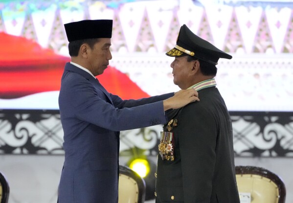 Indonesian Defense Minister Prabowo Subianto, right, receives four-star general epaulettes, from President Joko Widodo during a ceremony at the Armed Forces Headquarters in Jakarta, Indonesia, Wednesday, Feb. 28, 2024. President Joko Widodo on Wednesday awarded an honorary four-star general rank to Defense Minister Subianto, a former high-ranking army officer who is linked to human rights abuses and who emerged as the apparent winner of the Feb. 14 presidential election.(AP Photo/Achmad Ibrahim)