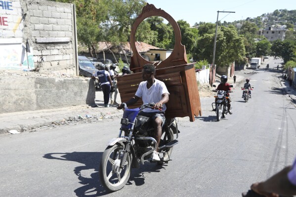 A resident, with a dresser attached to the back of his motorbike, flees his home escaping gang violence in the Solino neighborhood of Port-au-Prince, Haiti, Saturday, Oct. 26, 2024. (AP Photo/Odelyn Joseph)