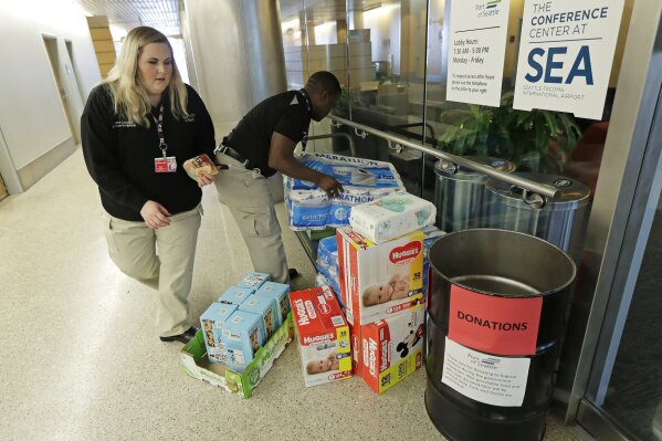 
              Port of Seattle workers Danica Doyle, left, and Matondo Wawa, right, collect items donated to federal workers affected by the government shutdown at Seattle-Tacoma International Airport, Friday, Jan. 25, 2019 in Seattle. The workers said the Port would continue to accept donations despite a short-term deal to reopen the government for three weeks announced Friday by President Donald Trump. (AP Photo/Ted S. Warren)
            