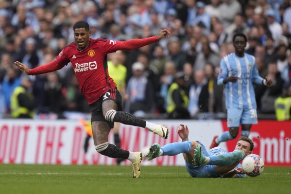 Manchester United's Marcus Rashford challenges for the ball with Coventry City's Benjamin David Sheaf, bottom, during the English FA Cup semifinal soccer match between Coventry City and Manchester United at Wembley stadium in London, Sunday, April 21, 2024. (AP Photo/Alastair Grant)
