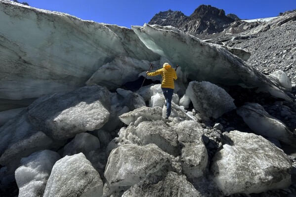 Glaciologist Andrea Fischer from the Austrian Academy of Sciences climbs up at the Jamtalferner Glacier near Galtuer, Austria, Wednesday, Sept. 6, 2023. (AP Photo/Matthias Schrader)