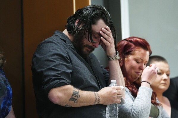 Devon Vestal, front, and his wife, Jess, react as they listen during a news conference to announce plans to sue the Littleton, Colo., school district for abuse suffered by their autistic child while riding the bus to class Tuesday, April 9, 2024, in Denver. (AP Photo/David Zalubowski)