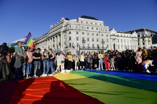 People unfurl a rainbow flag during an LGBT rights demonstration in front of the Hungarian Parliament building in Budapest, Hungary on June. 14, 2021. During the protest human rights activists called on lawmakers in Hungary to reject legislation banning any content portraying or promoting homosexuality or sex reassignment to anyone under 18. The bills, aiming at fighting pedophilia, have various amendments which would outlaw any depiction or discussion of different gender identities to youth in the public sphere.  (Szilard Koszticsak/MTI via AP)