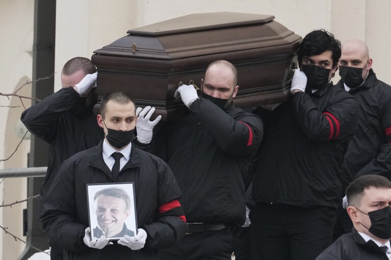 FILE - Workers carry the coffin and a portrait of Russian opposition leader Alexei Navalny out of a church in Moscow on March 1, 2024. Voters are heading to the polls in Russia for a three-day presidential election that is all but certain to extend President Vladimir Putin's rule after he clamped down on dissent. His political opponents are either in jail or in exile abroad, and Navalny, the fiercest of them, died in a remote Arctic penal colony recently. (AP Photo, File)