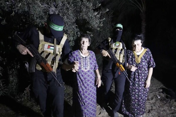 This image taken from video released by Al Qassam brigades on its Telegram channel, shows Yocheved Lifshitz, 85, center, and Nurit Cooper, 79, being escorted by Hamas as they are released to the Red Cross in an unknown location, Monday, Oct. 23, 2023. (Al Qassam brigades via AP)