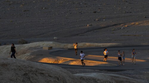 People run to get sunset photos at Zabriskie Point on Saturday, July 8, 2023, in Death Valley National Park, Calif. July is the hottest month at the park with an average high of 116 degrees (46.5 Celsius). (AP Photo/Ty ONeil)