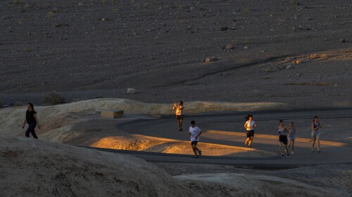 La gente corre para tomar fotos del atardecer en Zabriskie Point el sábado 8 de julio de 2023, en el Parque Nacional Death Valley, California. Julio es el mes más caluroso en el parque con una temperatura máxima promedio de 116 grados (46,5 grados Celsius). (Foto AP/Ty ONeil)