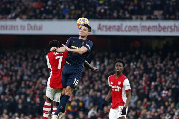 Burnley's Ashley Westwood, center, jumps for the ball with Arsenal's Bukayo Saka during the English Premier League soccer match between Arsenal and Burnley at Emirates stadium in London, Sunday, Jan. 23, 2022. (AP Photo/David Cliff)