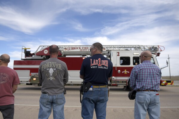 Lubbock county first responders pause as the procession for Fritch Fire Chief Zeb Smith passes by, Tuesday, March 5, 2024, in Lubbock, Texas. Smith suffered a medical emergency and died while fighting a fire Tuesday. (Annie Rice/Lubbock Avalanche-Journal via AP)