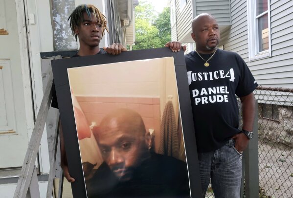 CORRECTS TO BROTHER NOT UNCLE OF DANIEL PRUDE - FILE - In this Sept. 3, 2020, file photo, Joe Prude, right, brother of Daniel Prude, and Daniel's nephew Armin, stand with a picture of Daniel Prude in Rochester, N.Y. In a decision announced Tuesday, Feb. 23, 2021, a grand jury voted not to charge officers shown on body camera video holding Daniel Prude down naked and handcuffed on a city street last winter until he stopped breathing. (AP Photo/Ted Shaffrey, File)