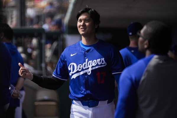 Los Angeles Dodgers designated hitter Shohei Ohtani walks in the dugout during the fourth inning of a spring training baseball game against the Chicago White Sox in Phoenix, Tuesday, Feb. 27, 2024. (AP Photo/Ashley Landis)