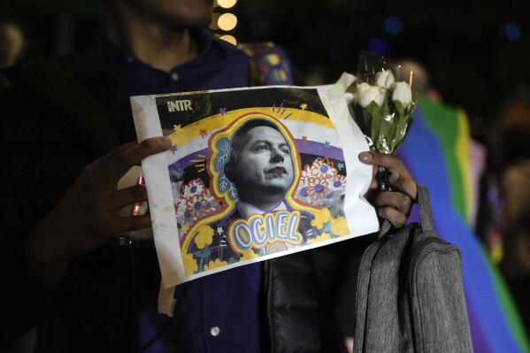 A demonstrator holds a picture of Aguascalientes state electoral court magistrate Jesus Ociel Baena in Mexico City, Monday, Nov. 13, 2023. The first openly nonbinary person to assume a judicial position in Mexico was found dead in their home Monday in the central Mexican city of Aguascalientes after receiving death threats because of their gender identity, authorities said. (AP Photo/Eduardo Verdugo)