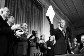 FILE - President Jimmy Carter holds up the Alaska National Interest Lands Conservation Act, which declared 104 million acres in Alaska as national parks, wildlife refuges and other conservation categories, after signing it into law at a ceremony at the White House in Washington, on Dec. 2, 1980. Carter on Monday, May 9, 2022, took the unusual step of weighing in on a court case involving his landmark conservation act and a remote refuge in Alaska. Carter filed a amicus brief in the longstanding legal dispute over efforts to build a road through the refuge, worried that the latest decision to allow a gravel road to provide residents access to an all-weather airport for medical evacuations goes beyond this one case and could allow millions of acres (hectares) to be opened for "adverse development." (AP Photo, File)