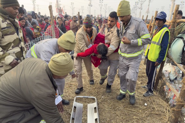 Security officers carry a woman out from the site of a stampede at the Sangam, the confluence of the Ganges, the Yamuna and the mythical Saraswati rivers, on "Mauni Amavasya" or new moon day during the Maha Kumbh festival, in Prayagraj, Uttar Pradesh, India, Wednesday, Jan. 29, 2025. (AP Photo/Rajesh Kumar Singh)