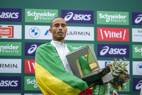 Uma Mulugeta of Ethiopia poses on the podium, after winning the men's race of the Paris marathon, in Paris, Sunday, April 7, 2024. (AP Photo/Lewis Joly)