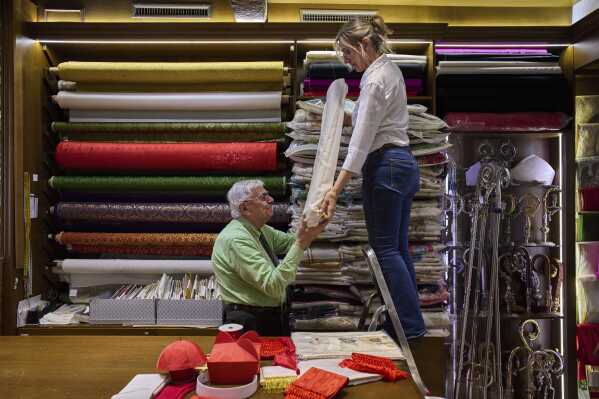 Italian tailor Raniero Mancinelli, 87, and her daughter Laura Mancinelli, 60, prepare the white fabric to create suits, in three different sizes, to be taken to the Vatican in the hope that it might be worn by the new pope, at their shop in Rome, Thursday April 24, 2025. (AP Photo/Bernat Armangue)