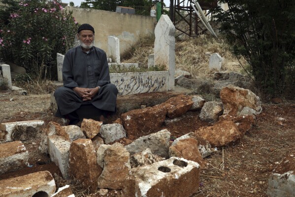 FILE - Mohammed Hassan Masto sits next to the grave of his brother Lutfi on May 7, 2023, in the village of Qorqanya, a rural area in northern Idlib province, Syria. Central Command said Thursday, May 2, 2024, an airstrike in Syria that was targeting an al-Qaida leader misidentified the intended target and killed Lutfi Hassan Masto instead. The investigation confirms early reports from residents and family members shortly after the attack. (AP Photo/Omar Albam, File)
