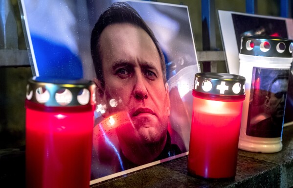 Candles and a photo of Russian opposition leader Alexei Navalny are placed at the fence of the meanwhile closed Russian consulate in Frankfurt, Germany, Friday, Feb. 16, 2024. Navalny, who crusaded against official corruption and staged massive anti-Kremlin protests as President Vladimir Putin's fiercest foe, died Friday in the Arctic penal colony where he was serving a 19-year sentence, Russia's prison agency said. He was 47. (AP Photo/Michael Probst)