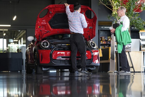 FILE - This photo provided by the Associated Press shows a salesperson shows an unsold 2024 Cooper SE electric hardtop to a prospective buyer as the vehicle sits on display on the showroom floor of a Mini dealership, Wednesday, May 1, 2024, in Highlands Ranch, Colo. (AP Photo/David Zalubowski, File)