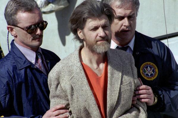 FILE - Theodore "Ted" Kaczynski is flanked by federal agents as he is led to a car from the federal courthouse in Helena, Mont., April 4, 1996. Kaczynski, known as the “Unabomber,” who carried out a 17-year bombing campaign that killed three people and injured 23 others, died by suicide, four people familiar with the matter told The Associated Press, Sunday, June 11, 2023. (AP Photo/John Youngbear, File)