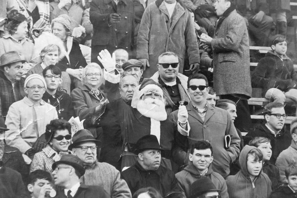 FILE - This 1967 file photo shows Philadelphia Eagles fan Frank Olivo, center, wearing his Santa suit in the stands of a Philadelphia Eagles game in 1967. Olivo, known as the Santa who was booed and dodged snowballs during halftime at a 1968 Eagles game, believes the infamous snowball episode launched the Philadelphia Eagles reputation for boorish fans. (The Philadelphia Inquirer via AP)