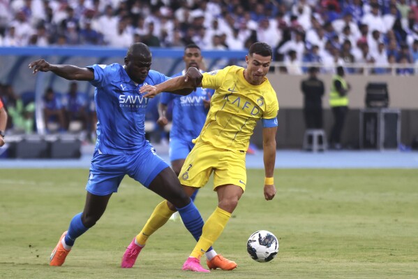 Al-Nassr's Cristiano Ronaldo, right, fights for the ball against Al-Hilal's Kalidou Koulibaly during the Arab Club Champions Cup between Al-Nassr and Al-Hilal at King Fahd Stadium in Taif, Saudi Arabia, Saturday, Aug. 12, 2023. (AP Photo/Samah Zidan)