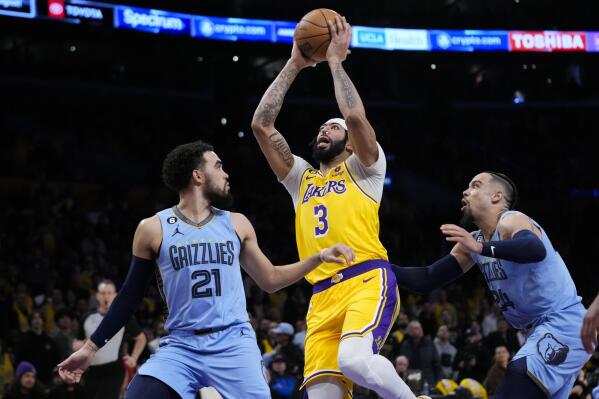 Los Angeles Lakers' Anthony Davis (3) goes up for a basket past Memphis Grizzlies' Tyus Jones (21) and Dillon Brooks (24) during the first half of an NBA basketball game Tuesday, March 7, 2023, in Los Angeles. (AP Photo/Jae C. Hong)