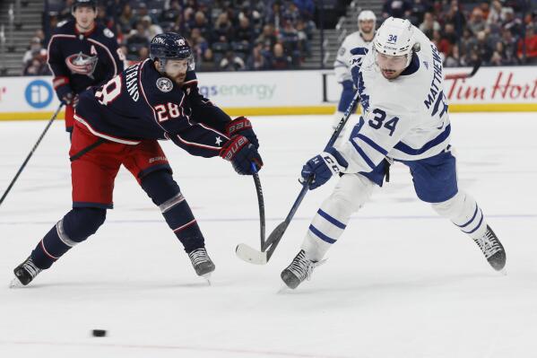 Toronto Maple Leafs' Auston Matthews, right, shoots the puck past Columbus Blue Jackets' Oliver Bjorkstrand during the third period of an NHL hockey game Monday, March 7, 2022, in Columbus, Ohio. (AP Photo/Jay LaPrete)