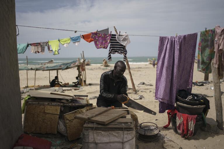 Djiby Diop, 65, repairs a container to stock the fish at his home on the beachfront in Saint Louis, Senegal, Wednesday, Jan. 18, 2023. Diop has two grandchildren who he says left the school due to the economic crisis. (AP Photo/Leo Correa)