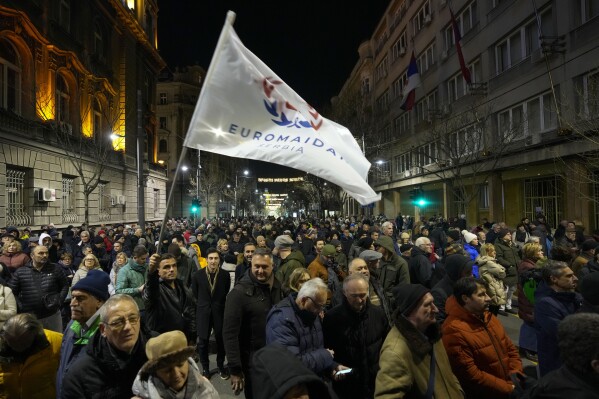 A protester waves a flag that reads: "EUROMAIDAN Serbia"during a rally in downtown Belgrade, Serbia, Tuesday, Jan. 16, 2024. People rallied accusing the populist authorities of President Aleksandar Vucic of orchestrating a fraud during the Dec. 17 parliamentary and local election. The ruling Serbian Progressive Party was declared the election winner but the main opposition alliance, Serbia Against Violence, has claimed the election was stolen, particularly in the vote for the Belgrade city authorities. (AP Photo/Darko Vojinovic)