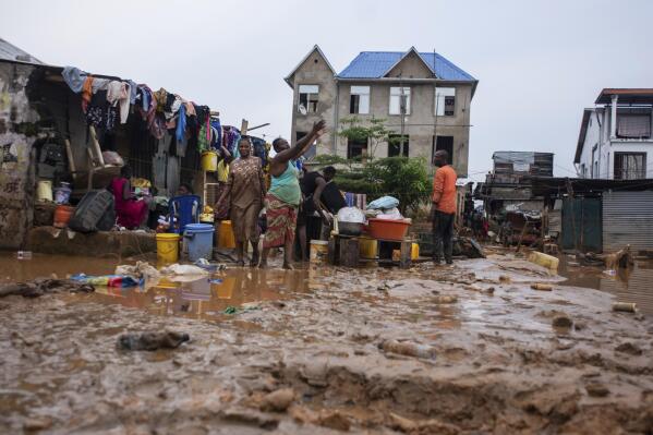 Residents clean up following torrential rains in Kinshasa, Democratic Republic of Congo, Tuesday, Dec. 13, 2022. At least 100 people have been killed and dozens injured by widespread floods and landslides caused by the rains. (AP Photo/Samy Ntumba Shambuyi)