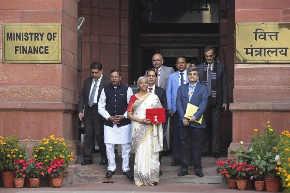 Indian Finance Minister Nirmala Sitharaman, carrying a red pouch containing budget documents, poses for a photograph with colleagues as she arrives to present the federal budget in the Parliament in New Delhi, India, Saturday, Feb. 1, 2025. (AP Photo)