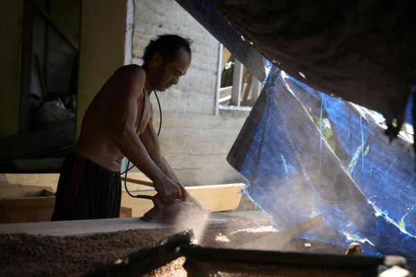 Jembong, a boat maker, operates an electric planer at his workshop on Karampuang Island, in West Sulawesi, Indonesia, Thursday, Dec. 22, 2022. For the energy-intensive power tools he uses to handcraft boats from his home, he needs diesel. (AP Photo/Dita Alangkara)