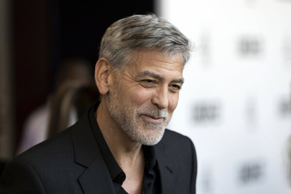 FILE - In this Wednesday, May 15, 2019, file photo, actor George Clooney talks to reporters on arrival at the premiere of the television mini-series "Catch22," in London. Clooney was honored Monday, Dec. 7, 2020, by co-stars and colleagues at the annual film benefit for the Museum of Modern Art, held virtually. (Photo by Grant Pollard/Invision/AP, File)