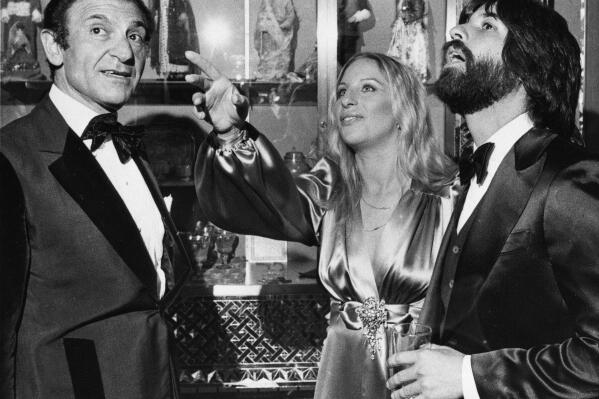 FILE - Iran's Then-Ambassador Ardeshir Zahedi, left, talks with actress Barbra Streisand and her escort Jon Peters as they admire the Iranian Embassy March 8, 1975 during a reception in Washington, D.C. Zahedi, Iran's flamboyant ambassador to the United States under its ruling shah, who charmed both the stars and politicians with his lavish parties until the 1979 Islamic Revolution, has died, Iranian state media reported Thursday, Nov. 18, 2021. He was 93. (AP Photo/Charles W. Harrity, File)
