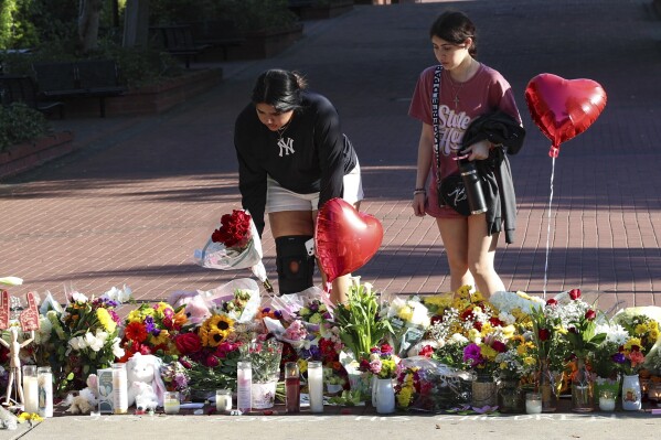 Students place flowers on a stretch of sidewalk near the center of the Florida State campus in sight of the Student Union building, Tallahassee, Fla., Friday, April 18, 2025. (AP Photo/Gary McCullough)