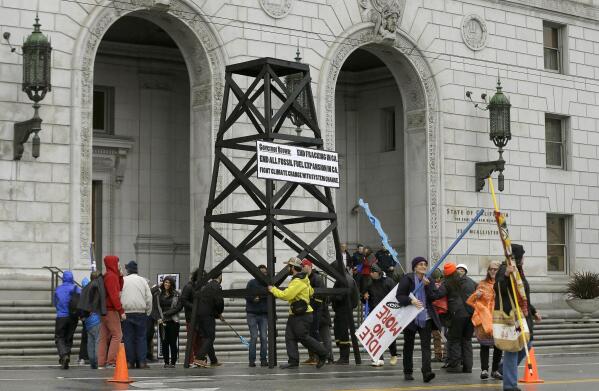 FILE - In this Feb. 6, 2015, file photo, protesters prepare to take down a makeshift oil derrick that was set up in front of the California State Office Building to protest fracking in San Francisco. California regulators are citing climate change for the first time as they deny new permits for hydraulic fracturing, a process used to extract oil and gas from the ground. In denying 50 fracking permits this year, the state's oil and gas supervisor said he was using his discretion to protect public health, safety and environmental quality and to mitigate greenhouse gas emissions. (AP Photo/Jeff Chiu, File)