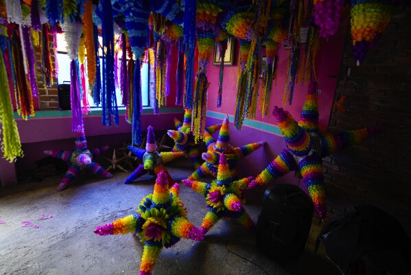 Las tradicionales "piñatas" navideñas que estarán llenas de frutas y dulces se exhiben en una pequeña empresa familiar en Acolman, justo al norte de la Ciudad de México, el miércoles 13 de diciembre de 2023. Este estilo de piñata tiene un origen religioso, con cada cono representa uno de los siete pecados capitales, y golpear el globo con un palo es un golpe simbólico contra el pecado.  (Foto AP/Fernando Llano)