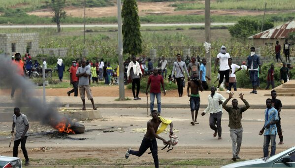 Protesters throw rocks at policemen during an attack on South African business, in Abuja, Nigeria, Wednesday Sept. 4, 2019. South African-owned businesses operating in Nigeria are being targeted with violence in retaliation for xenophobic attacks carried out against Africans working in South Africa. Police in South African arrested more than 100 people in five areas impacted by days of violence in Johannesburg and Pretoria. (AP Photo)