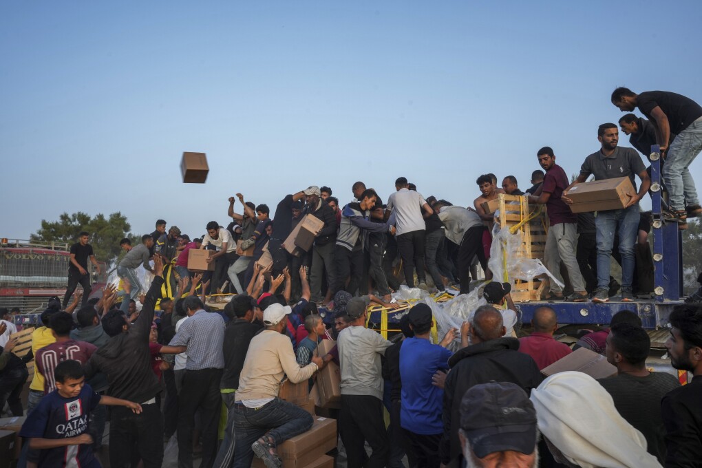 Palestinians are storming trucks loaded with humanitarian aid brought in through a new U.S.-built pier, in the central Gaza Strip, Saturday, May 18, 2024. (AP Photo/Abdel Kareem Hana)