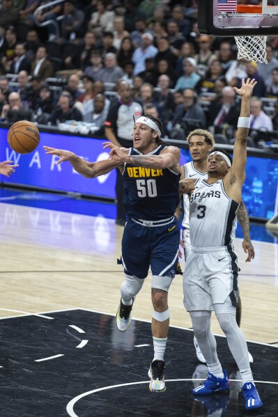Denver Nuggets forward Aaron Gordon (50) passes the ball away from San Antonio Spurs forward Keldon Johnson (3) during the first half of an NBA basketball game, Friday, March 15, 2024, in Austin, Texas. (AP Photo/Stephen Spillman)