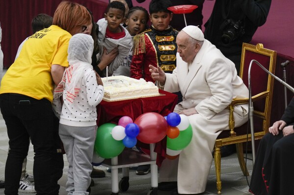 Pope Francis blows a candle on a cake as he celebrates his birthday with children assisted by the Santa Marta dispensary during an audience in the Paul VI Hall, at the Vatican, Sunday, Dec. 17, 2023. Pope Francis turnes 87 on Dec.17. (AP Photo/Alessandra Tarantino)