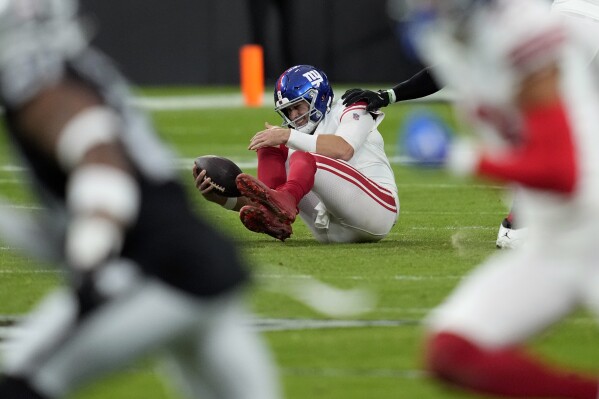 New York Giants quarterback Daniel Jones grimaces after a sack during the first half of an NFL football game against the Las Vegas Raiders, Sunday, Nov. 5, 2023, in Las Vegas. (AP Photo/John Locher)