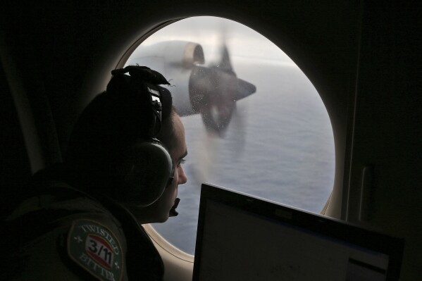 FILE - Flight officer Rayan Gharazeddine scans the water in the southern Indian Ocean off Australia from a Royal Australian Air Force AP-3C Orion during a search for the missing Malaysia Airlines Flight MH370 on March 22, 2014. A decade ago this week, a Malaysia Airlines flight vanished without a trace to become one of aviation’s biggest mystery. Investigators still do not know exactly what happened to the plane and its 239 passengers. (AP Photo/Rob Griffith, File)