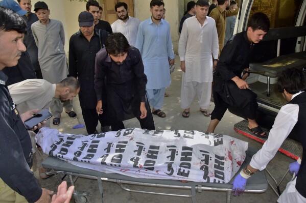 Relatives prepare to load a body of a police officer killed by unknown gunmen into a vehicle at a hospital in Quetta, Pakistan Tuesday, Aug. 1, 2023. Gunmen on motorcycles opened fire on police escorting a team of polio workers on Tuesday during a door-to-door vaccination campaign in the southwest, killing two police officers before fleeing, police said. (AP Photo/Arshad Butt)