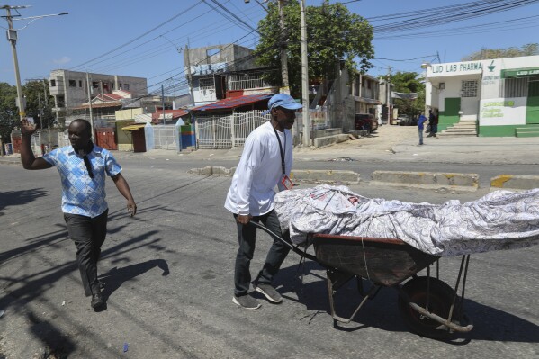 People transport the body of a man who died during a gang attack in the Delmas neighborhood of Port-au-Prince, Haiti, Tuesday, Feb. 25, 2025. (AP Photo/Odelyn Joseph)
