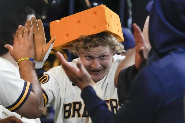 Milwaukee Brewers' Willy Adames, right, places a cheesehead hat on