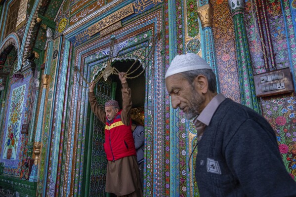A Kashmiri man, left, touches in reverence a chain at the entrance to the shrine of Shah-e-Hamadan as he leaves after offering prayers on the third Friday of Ramadan in Srinagar, Indian controlled Kashmir, Friday, April 7, 2023. Muslims across the world are marking the holy month of Ramadan, a period of intense prayer, self-discipline, dawn-to-dusk fasting and nightly feasts. (AP Photo/Dar Yasin)